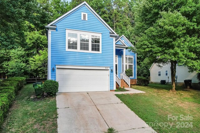 view of property featuring a garage and a front lawn