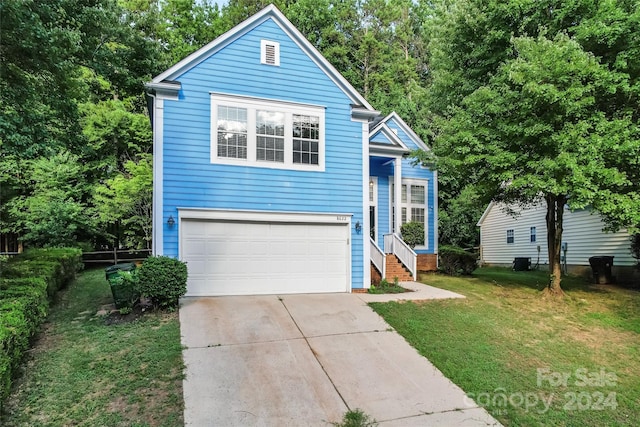 view of property featuring a garage and a front lawn