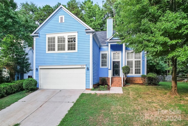 view of property featuring a garage and a front lawn