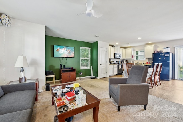 carpeted living room featuring ceiling fan, sink, and a healthy amount of sunlight