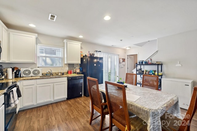 kitchen with white cabinetry, light hardwood / wood-style flooring, black appliances, and stone countertops