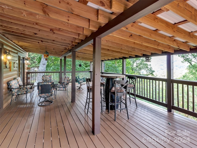 wooden terrace featuring exterior bar and outdoor dining area