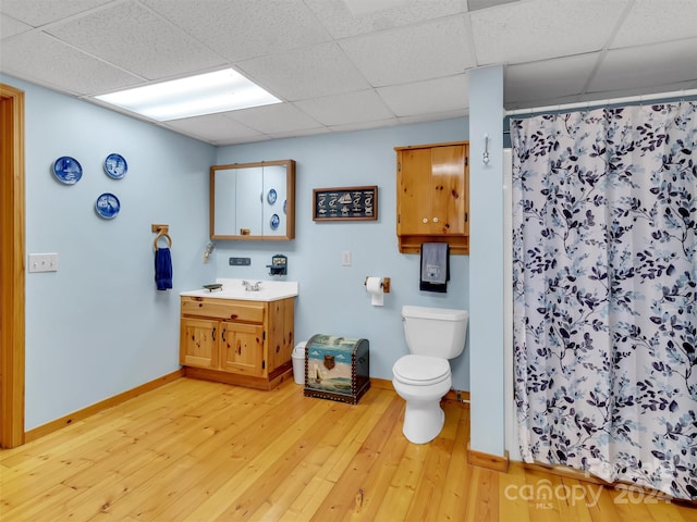 bathroom with a drop ceiling, vanity, hardwood / wood-style floors, and toilet