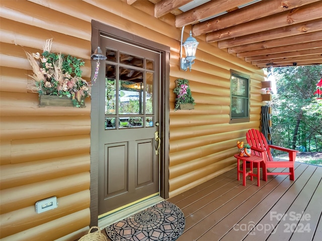 doorway to property with faux log siding and a porch