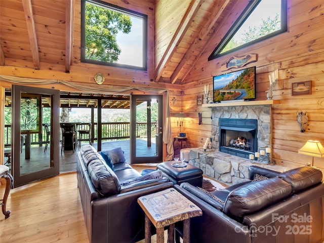 living room with beam ceiling, wooden walls, light wood-style flooring, and a fireplace