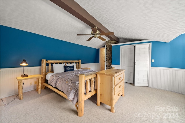 carpeted bedroom featuring ceiling fan, vaulted ceiling with beams, and a textured ceiling