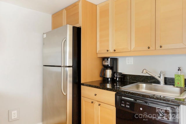 kitchen with sink, dark stone counters, black dishwasher, light brown cabinets, and stainless steel fridge