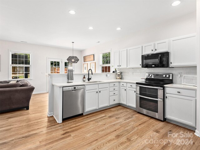 kitchen featuring decorative light fixtures, light hardwood / wood-style floors, sink, stainless steel appliances, and white cabinets