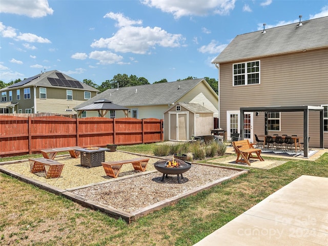 view of yard featuring an outdoor fire pit, a gazebo, a storage unit, and a patio