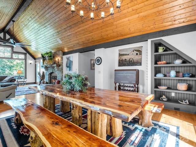 dining room featuring hardwood / wood-style floors, wooden ceiling, ceiling fan with notable chandelier, vaulted ceiling with beams, and a fireplace