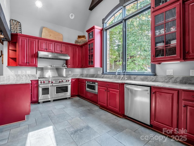 kitchen featuring light stone counters, sink, stainless steel appliances, and vaulted ceiling