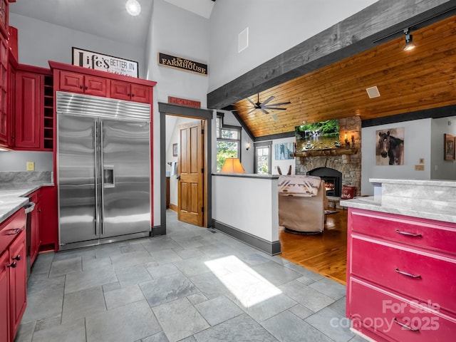 kitchen with ceiling fan, stainless steel built in fridge, wooden ceiling, vaulted ceiling, and a fireplace