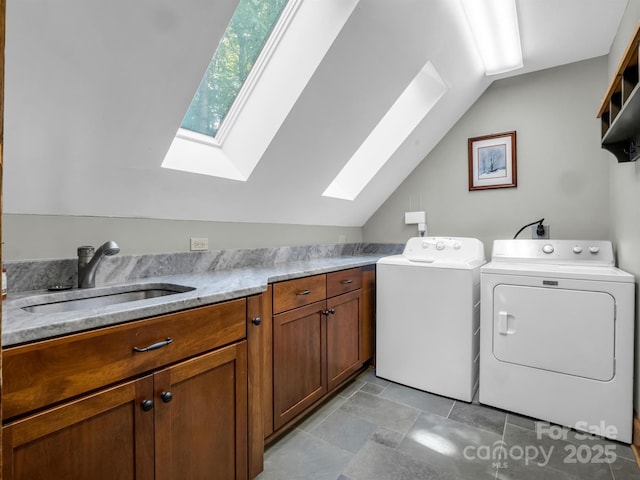 clothes washing area with cabinets, a skylight, sink, and washing machine and clothes dryer