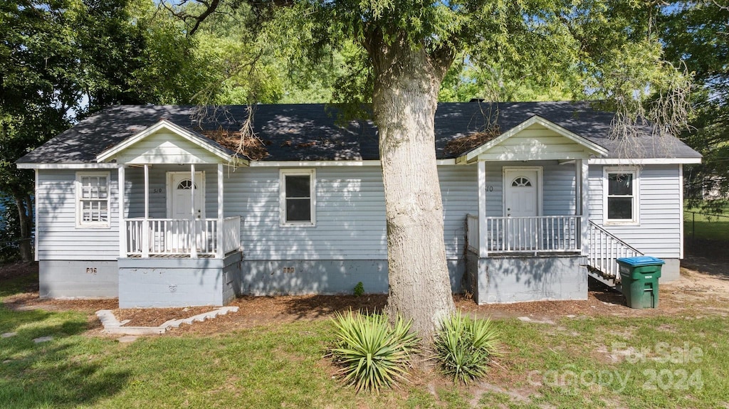 bungalow-style home featuring covered porch and a front lawn