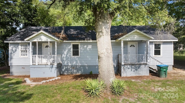 bungalow-style home featuring covered porch and a front lawn