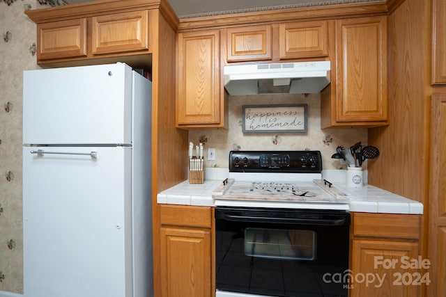 kitchen with decorative backsplash, tile counters, and white appliances