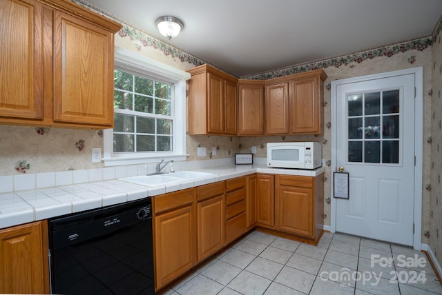 kitchen featuring tile counters, dishwasher, light tile patterned floors, and sink