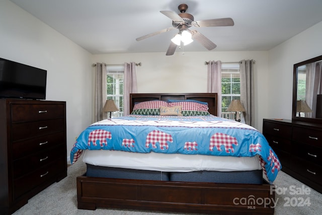 carpeted bedroom featuring multiple windows and ceiling fan