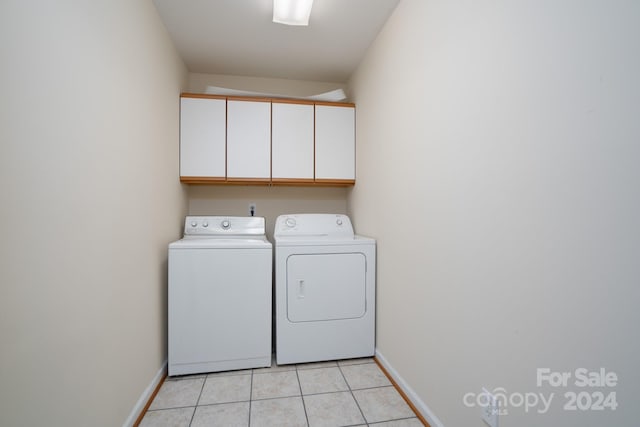 clothes washing area featuring light tile patterned flooring, cabinets, and separate washer and dryer