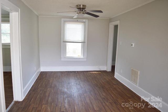 empty room featuring dark hardwood / wood-style floors, crown molding, and a healthy amount of sunlight