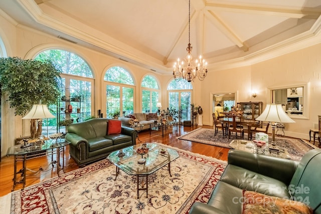 living room featuring a wealth of natural light, hardwood / wood-style flooring, a towering ceiling, and a chandelier