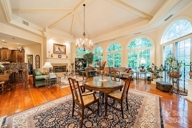 dining area with a high ceiling, ornamental molding, wood-type flooring, and a notable chandelier