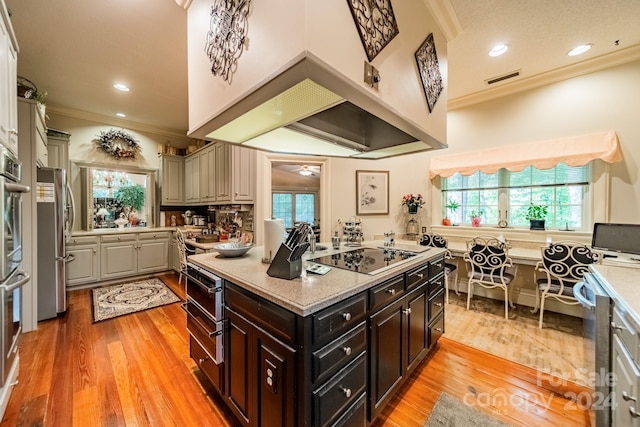 kitchen with dark brown cabinetry, crown molding, light hardwood / wood-style flooring, and black electric stovetop