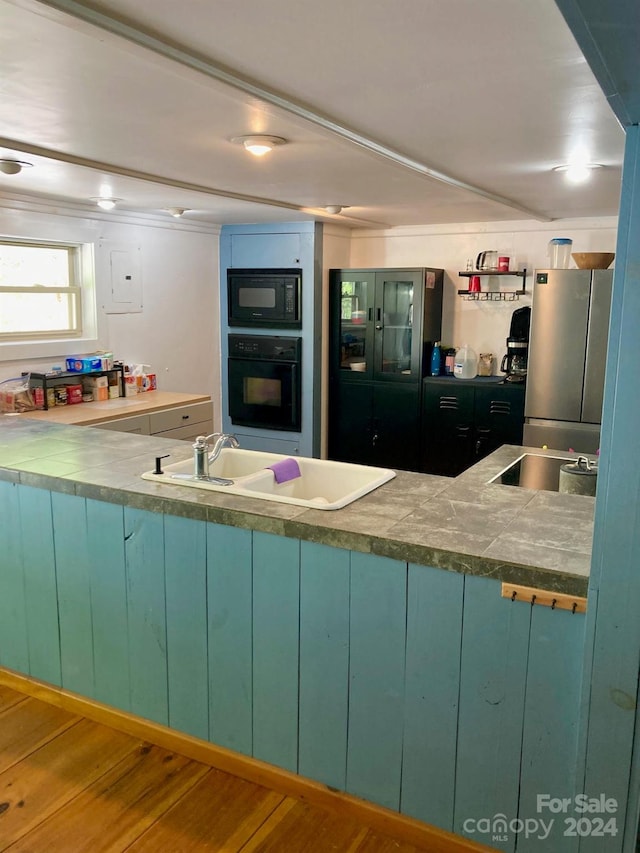 kitchen with green cabinets, sink, hardwood / wood-style flooring, and black appliances