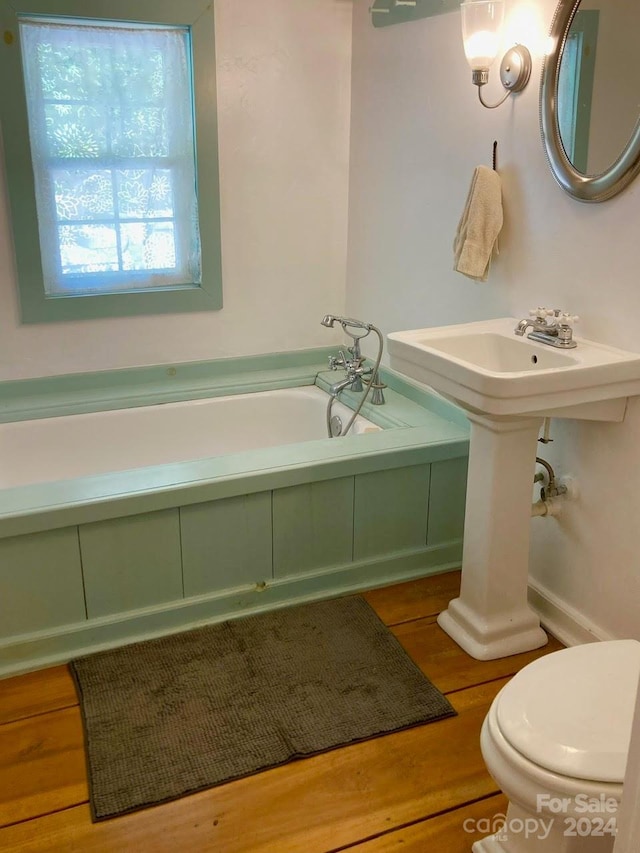 bathroom with toilet, hardwood / wood-style floors, and a tub