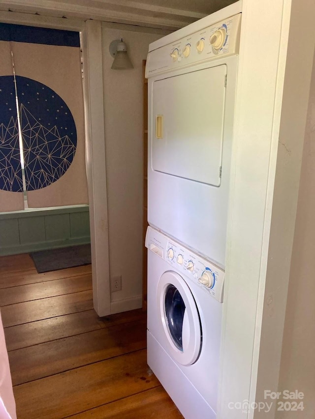 washroom featuring hardwood / wood-style flooring and stacked washer / dryer