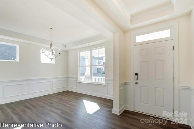 entrance foyer with a chandelier, a raised ceiling, and dark wood-type flooring