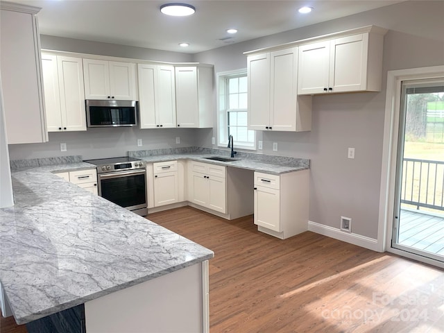 kitchen with light stone countertops, appliances with stainless steel finishes, light wood-type flooring, sink, and white cabinetry