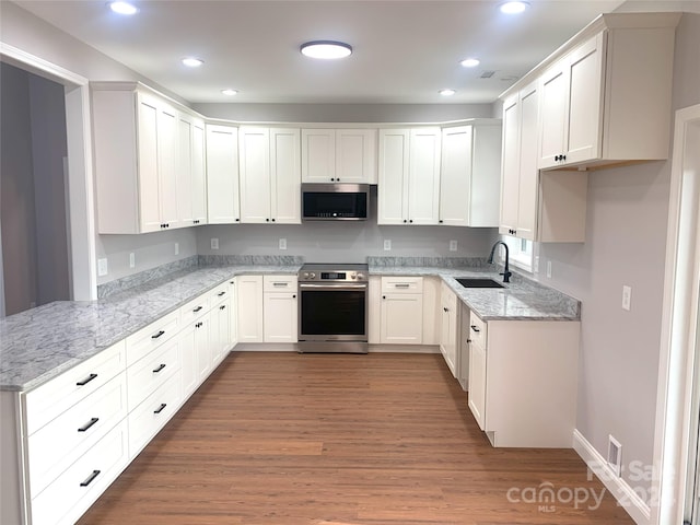 kitchen with white cabinets, wood-type flooring, stainless steel appliances, and sink