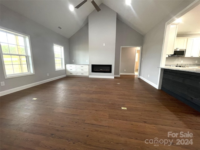 unfurnished living room featuring ceiling fan, dark hardwood / wood-style flooring, and high vaulted ceiling