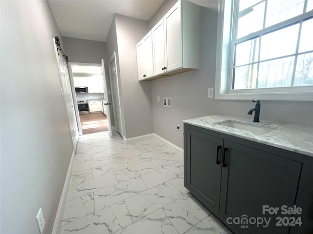 washroom with sink, cabinets, washer hookup, electric dryer hookup, and a barn door