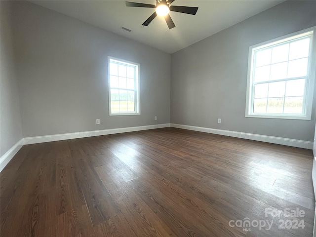 spare room with dark hardwood / wood-style floors, ceiling fan, and a healthy amount of sunlight