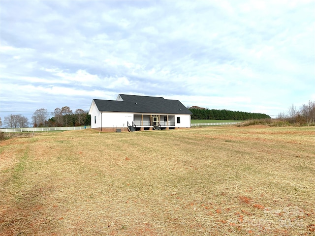 back of property featuring a lawn and a rural view