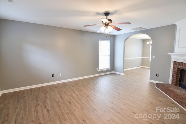 unfurnished living room with light wood-type flooring, a brick fireplace, and ceiling fan