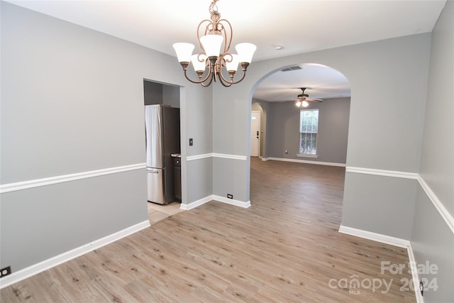 empty room with ceiling fan with notable chandelier and light hardwood / wood-style floors