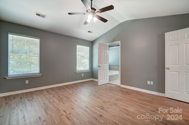 unfurnished bedroom featuring ceiling fan, multiple windows, light hardwood / wood-style flooring, and vaulted ceiling