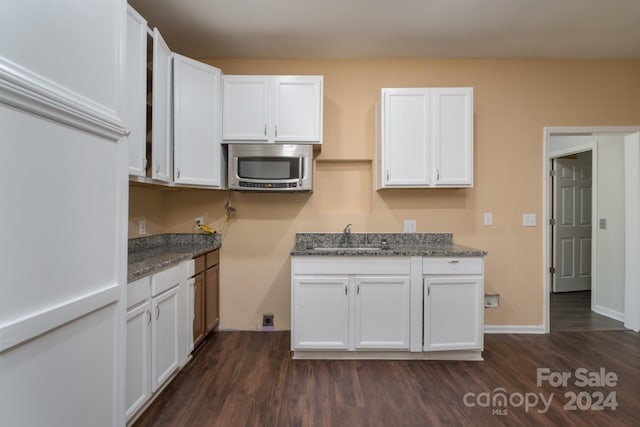 kitchen with dark hardwood / wood-style flooring, sink, dark stone countertops, and white cabinetry