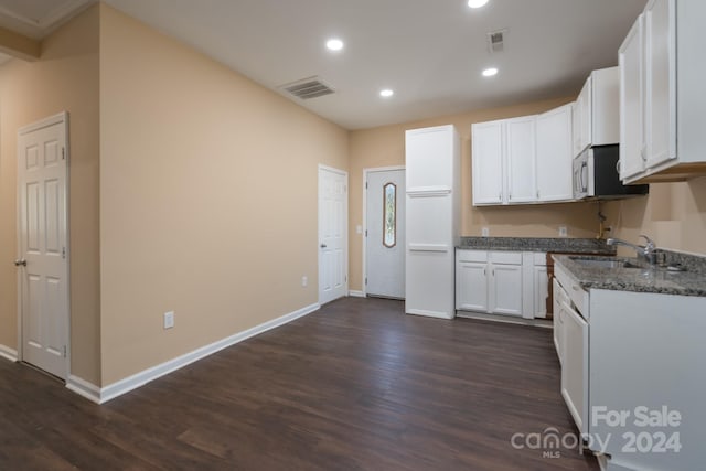 kitchen featuring dark wood-type flooring, sink, white cabinets, and dark stone countertops