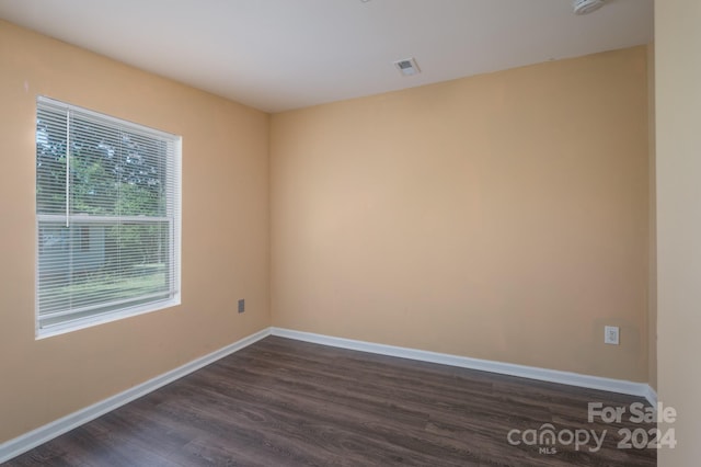 spare room with a wealth of natural light and dark hardwood / wood-style flooring