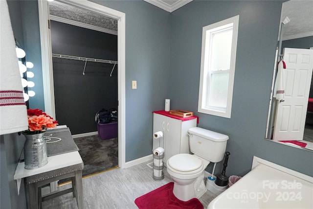 bathroom featuring crown molding, hardwood / wood-style floors, and toilet