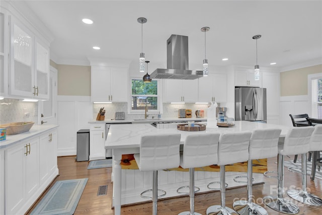 kitchen with stainless steel fridge, island range hood, white cabinetry, and a kitchen island