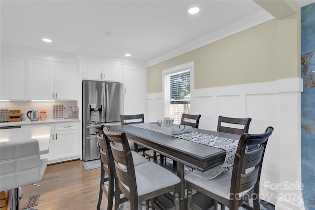 dining space featuring crown molding and light wood-type flooring