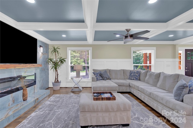 living room featuring a fireplace, hardwood / wood-style floors, beamed ceiling, coffered ceiling, and ornamental molding