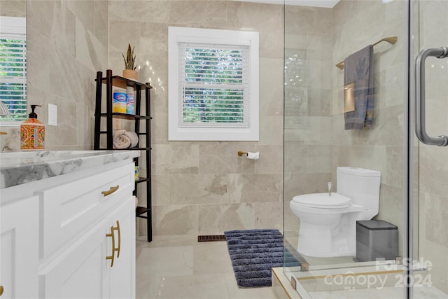 bathroom with a shower with shower door, tile walls, toilet, and vanity