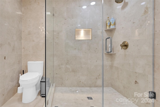 bathroom featuring toilet and a shower with shower door