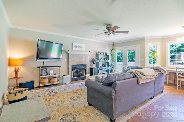 tiled living room with a textured ceiling, crown molding, french doors, and a fireplace